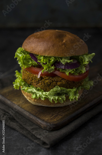 Vegan burger with vegetables on cutting board
