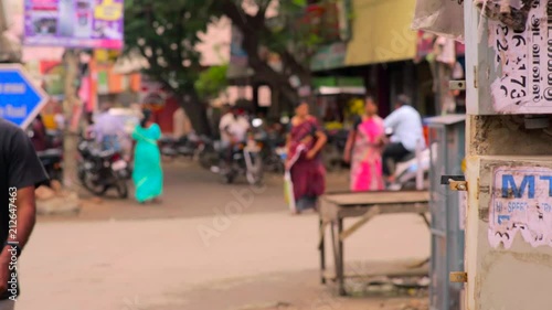 De-focused shot of people walk at street, young man comes towards camera