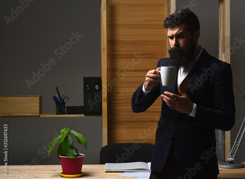 Silhouette of serious businessman drinking coffee in office. Hot coffee. Hot drinks. Portrait of considerable bearded businessman. Serious businessman in suit. Handsome bearded office worker. photo