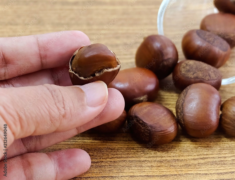Hand Holding Roasted Chestnuts From Small Glass Hand Holding Roasted Chestnuts From Small Glass