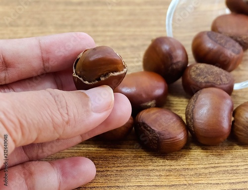 Hand Holding Roasted Chestnuts From Small Glass