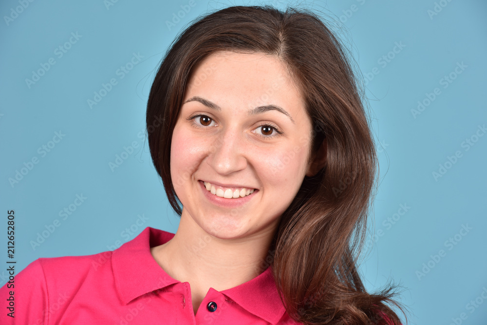 Portrait of a girl. A woman is smiling on a blue background. Good mood. Portrait of a girl. A woman is smiling on a blue background. Good mood.