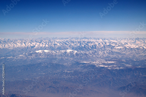 Mountains with snowy peaks on blue sky, aerial view. Planet earth natural landscape. Travel around world. Environment protection and ecology. Earth day is world birthday