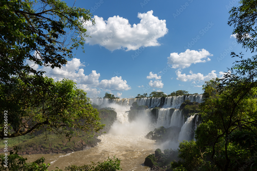 Waterfalls at Iguazu falls framed by trees and blue sky Waterfalls at Iguazu falls framed by trees and blue sky