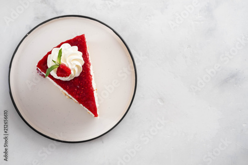 Closeup top view of raspberry cheesecake with mint leaves on white plate. Copy space.