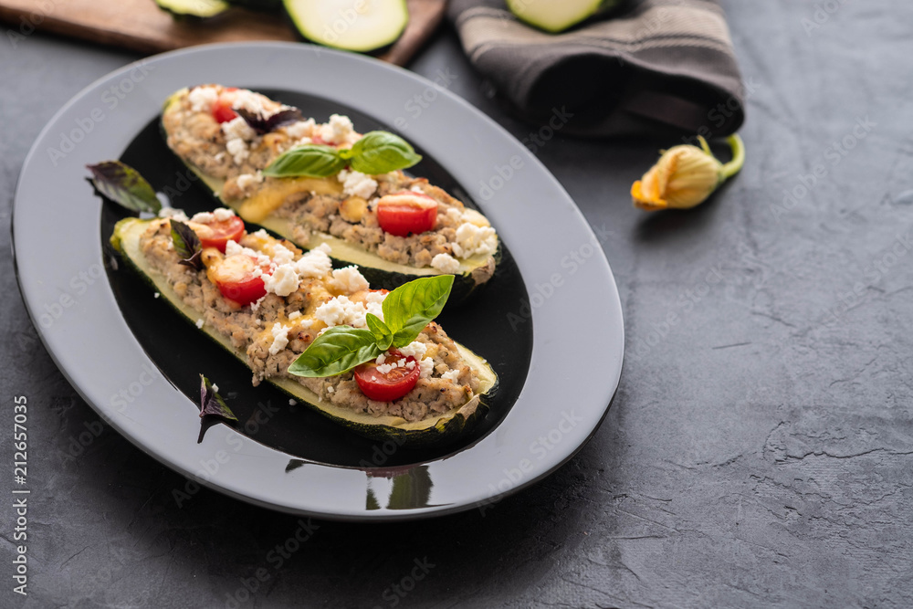 Zucchini stuffed with minced meat, cheese on a black background.Baked in oven. Copy space. Zucchini stuffed with minced meat, cheese on a black background.Baked in oven. Copy space.