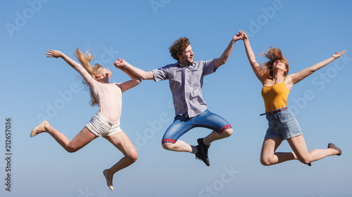 Carefree friends jumping on sky background.