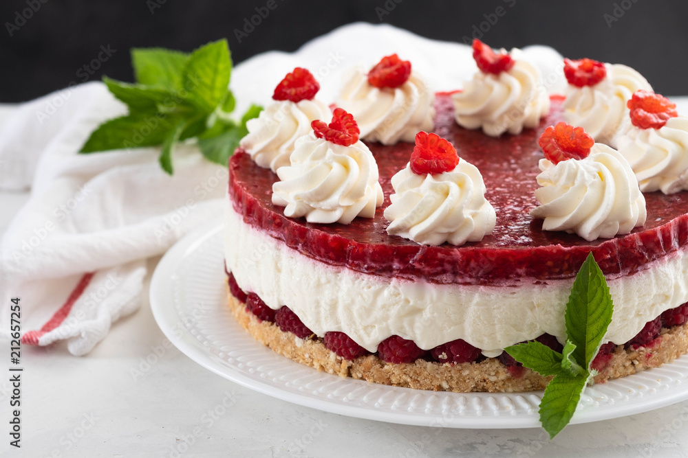 Raspberry cheesecake with whipped cream and fresh raspberries on a white plate.Copy space. Raspberry cheesecake with whipped cream and fresh raspberries on a white plate.Copy space.