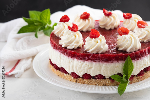 Raspberry cheesecake with whipped cream and fresh raspberries on a white plate.Copy space.