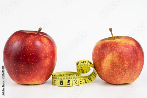 Red apples and a measure of tailor on a white table. Ripe fruits and a tailor's centimeter.