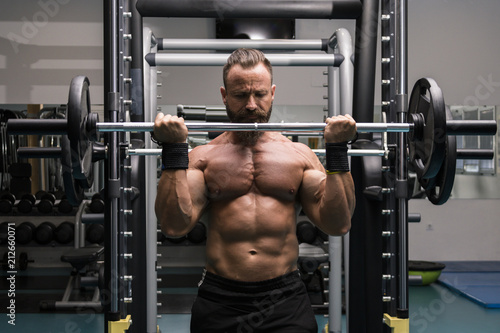 Hombre fuerte con grandes músculos levantando peso mientras entrena en el gimnasio. Ponerse en forma