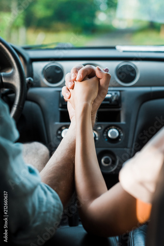 cropped image of couple holding hands and sitting in car © LIGHTFIELD STUDIOS