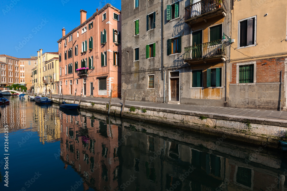 Colourful buildings reflect in a still canal, Venice, Italy