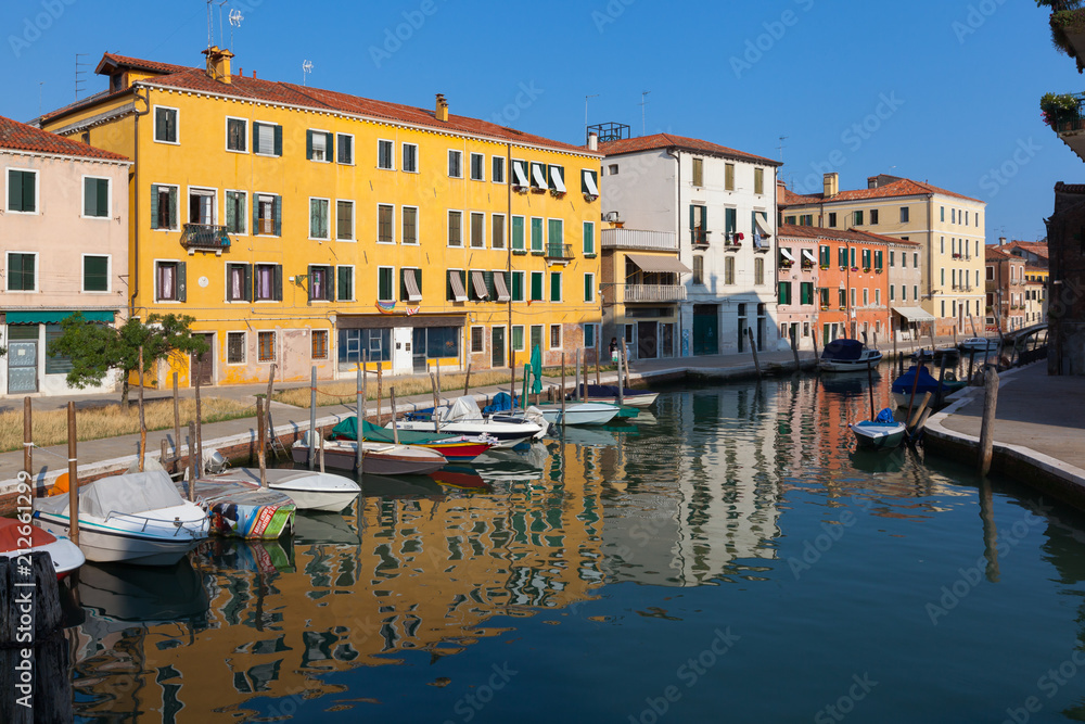 Colourful buildings and boats reflect a Venice canal. Italy
