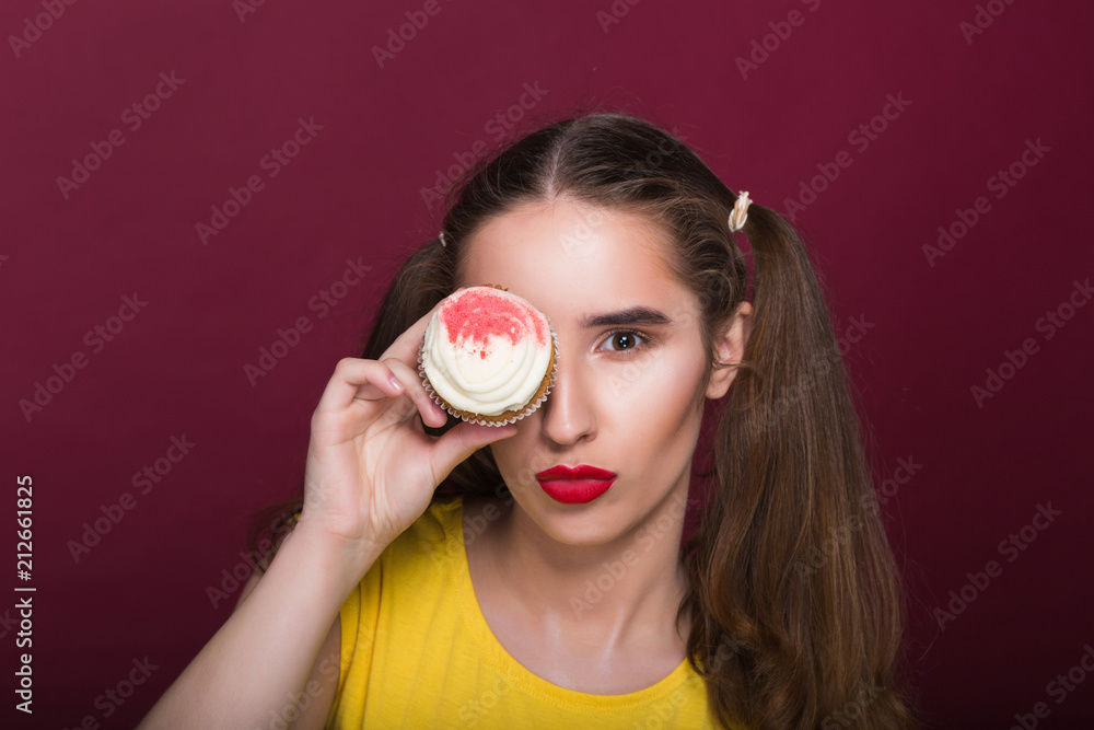 Wonderful brunette girl with bright makeup holding cheese cake near her eyes