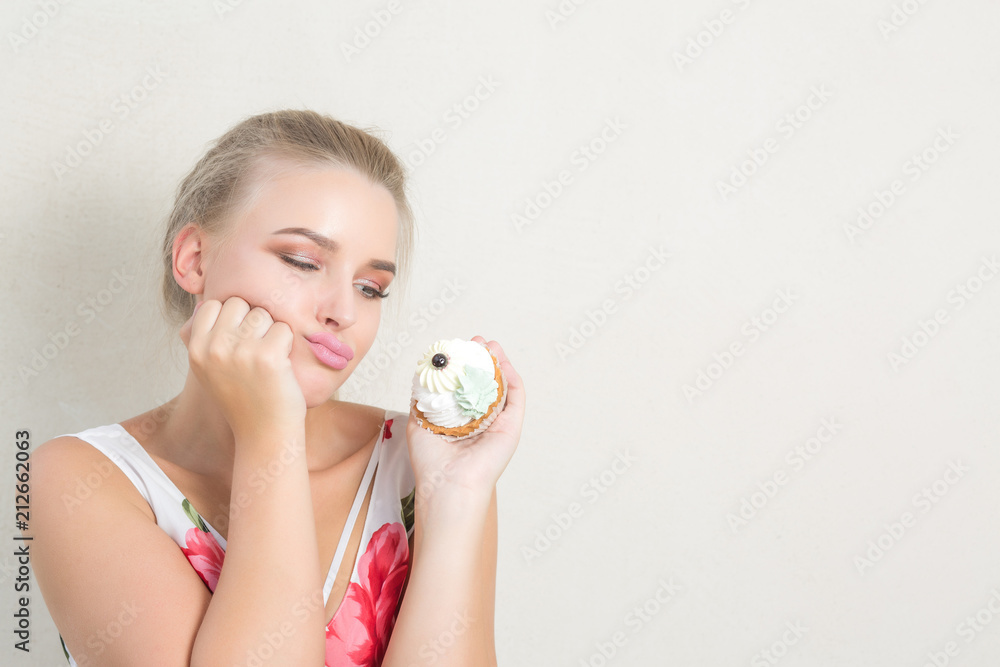 Frustrated dieting blonde lady holding delicious dessert with cream. Space for text
