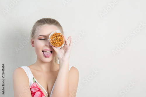 Playful blonde woman posing with palatable dessert with nuts. Empty space