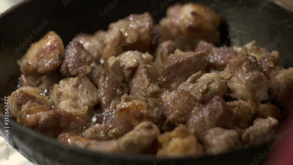 Сooking crispy fried pork. Frying meat pieces in the heated iron skillet closeup. Сooking crispy fried pork. Frying meat pieces in the heated iron skillet closeup.
