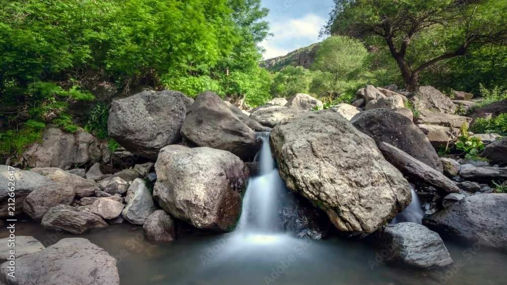 Beautiful mountain waterfall in the jungle forest. Water slow flow and fall down through big boulders and stones. Green tree foliage in the background. Zoom. 4K Slow Motion Photo Time Lapse Parallax Beautiful mountain waterfall in the jungle forest. Water slow flow and fall down through big boulders and stones. Green tree foliage in the background. Zoom. 4K Slow Motion Photo Time Lapse Parallax