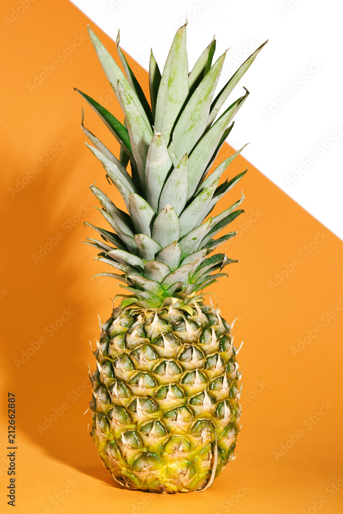 Fresh pineapple with green leaves. Tropical Fruit on an orange and white background. Creative concept Fresh pineapple with green leaves. Tropical Fruit on an orange and white background. Creative concept
