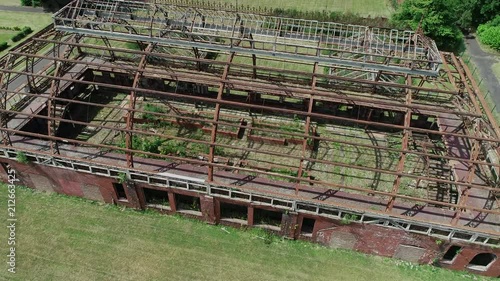 Aerial footage of the metal skeleton of a large abandoned glasshouse. photo