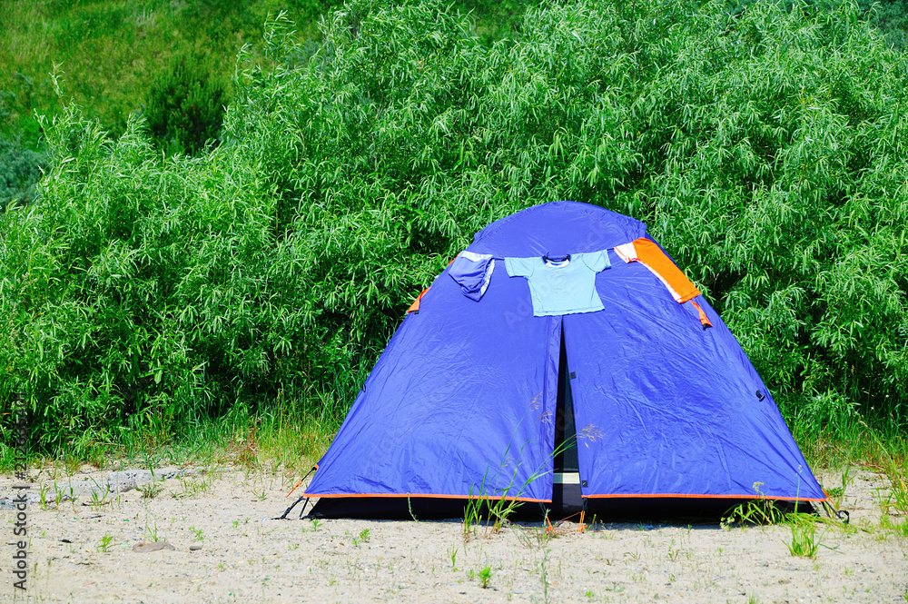Tourist blue tent on the beach with trees.