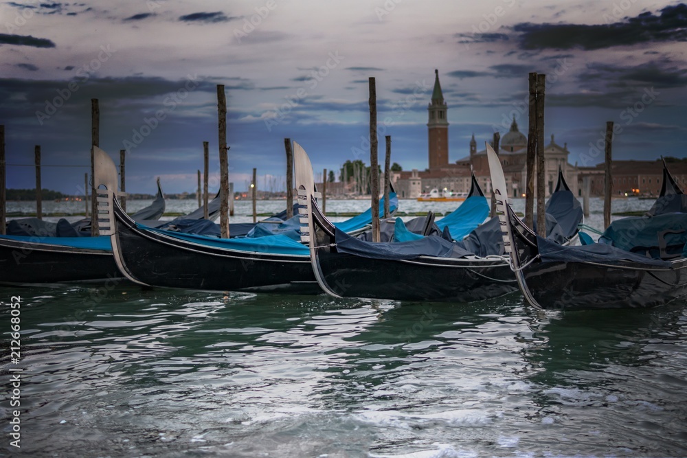 Many gondolas in Venice in Italy at twilight.