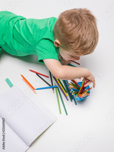 Kid lying on floor and drawing with colour pencils