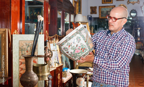 Portrait of mature man choosing vintage goods at antiques shop photo