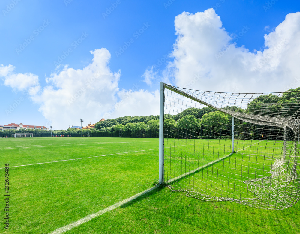 Fototapeta premium Green football field under blue sky background