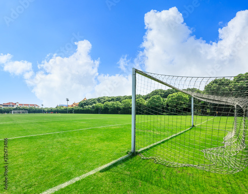Green football field under blue sky background © ABCDstock