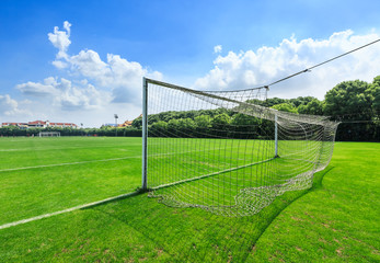 Green football field under blue sky background
