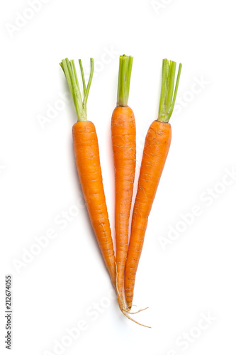 Three fresh young carrots with a cut tops isolated on white background..