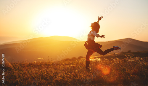 Happy woman jumping and enjoying life at sunset in mountains.