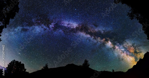 Panoramic astrophotography of whole visible Milky Way galaxy. Silhouette of mountains. Stars, nebula and stardust at night sky landscape photo