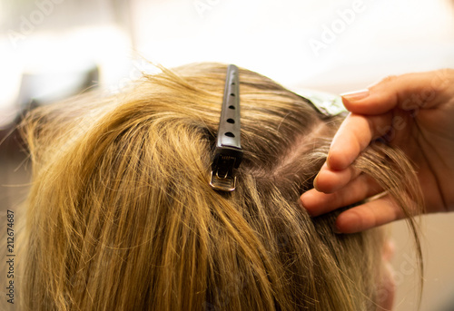 Blonde woman receiving haircut at a salon. Woman with blonde highlights. Hair foils on a female client. Master stylist cutting hair