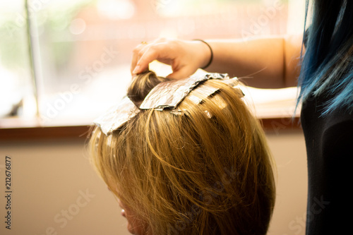 Blonde woman receiving haircut at a salon. Woman with blonde highlights. Hair foils on a female client. Master stylist cutting hair photo