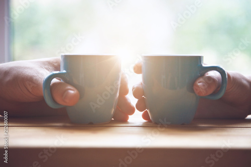 couple with two cups of morning coffee on sunrise light