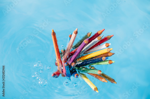 colored pencil floating in pool water photo