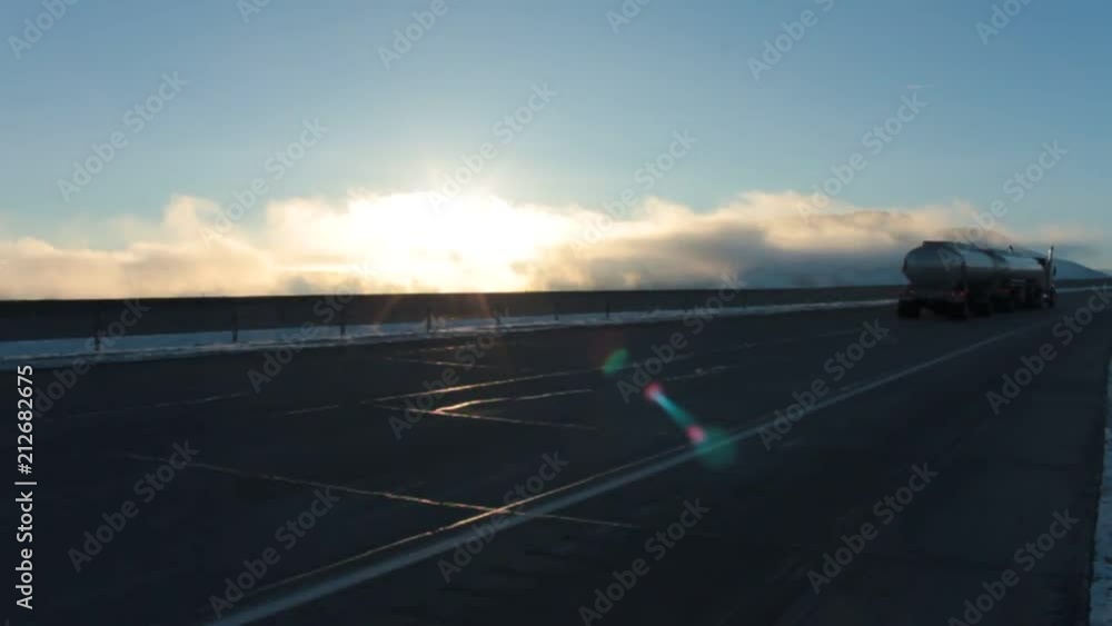 Big rig rolls down the highway, on a cold snowy morning as the sun rises. Big rig rolls down the highway, on a cold snowy morning as the sun rises.