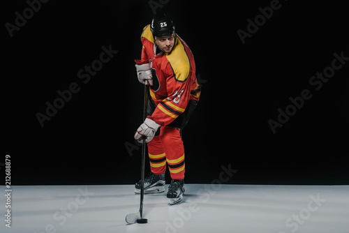 Canvas Print full length view of professional sportsman in skates playing ice hockey on black