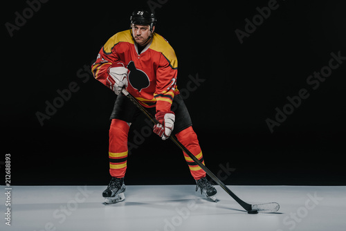 Photography full length view of professional young ice hockey player playing hockey on black