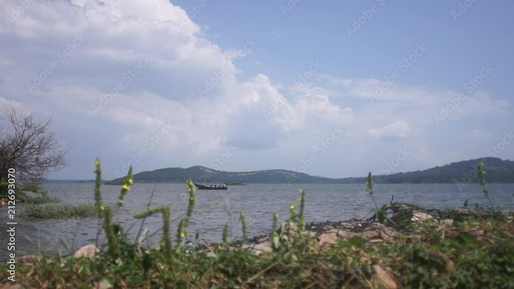 A small boat full of people travels along a peaceful river in Uganda. A small boat full of people travels along a peaceful river in Uganda.