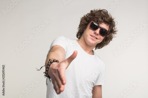 Portrait of cool guy in sunglasses stretching his hand in white t-shirt. photo