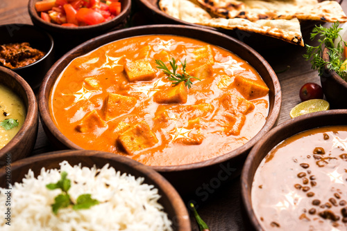 Assorted indian food for lunch or dinner, rice, lentils, paneer, dal makhani, naan, chutney, spices over moody background. selective focus
 photo