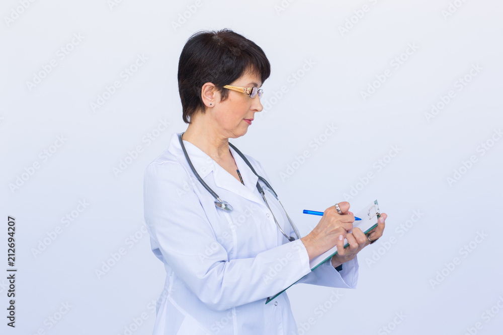 Portrait Of Female Doctor Writing On Clipboard Over a white background Portrait Of Female Doctor Writing On Clipboard Over a white background