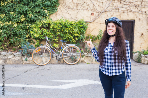 Cheerful woman represnt a bycycle on the background alley