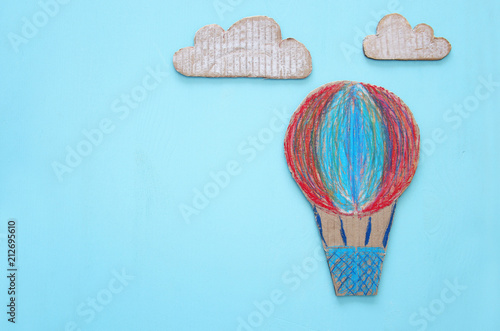 cardboard Hot air balloon cut from paper and painted over wooden blue background.