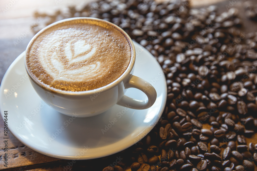 A cup of coffee with heart pattern in a white cup on wooden background A cup of coffee with heart pattern in a white cup on wooden background