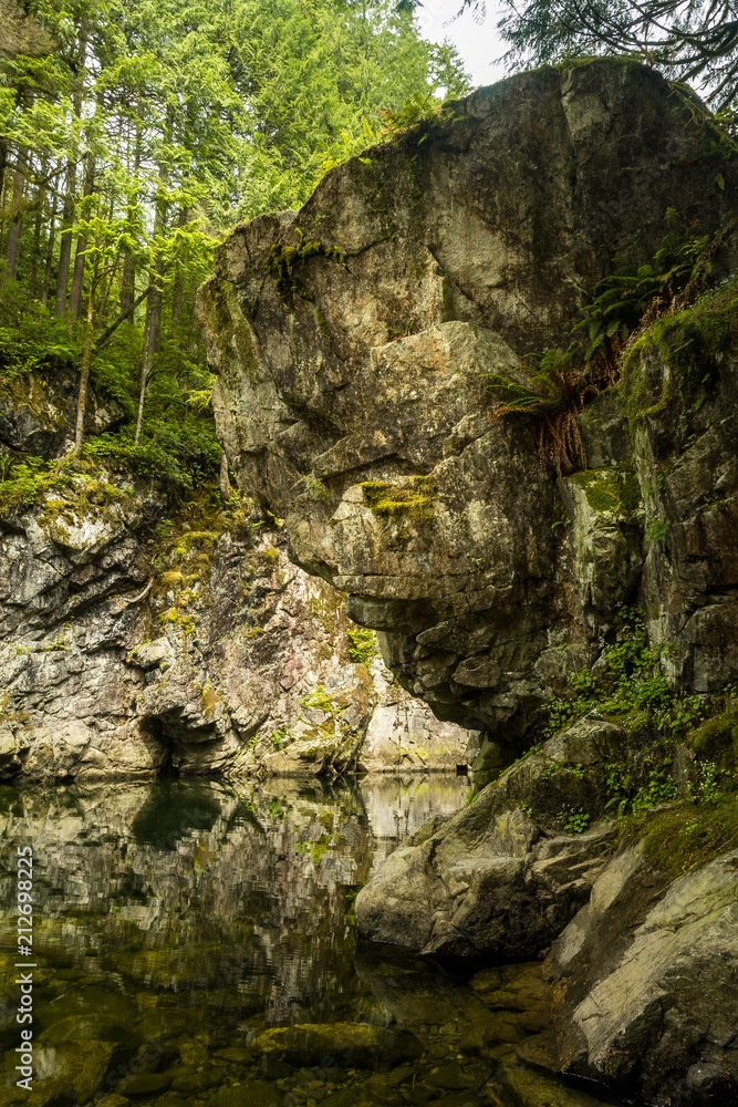 Giant rock face with reflection on the water in the creek